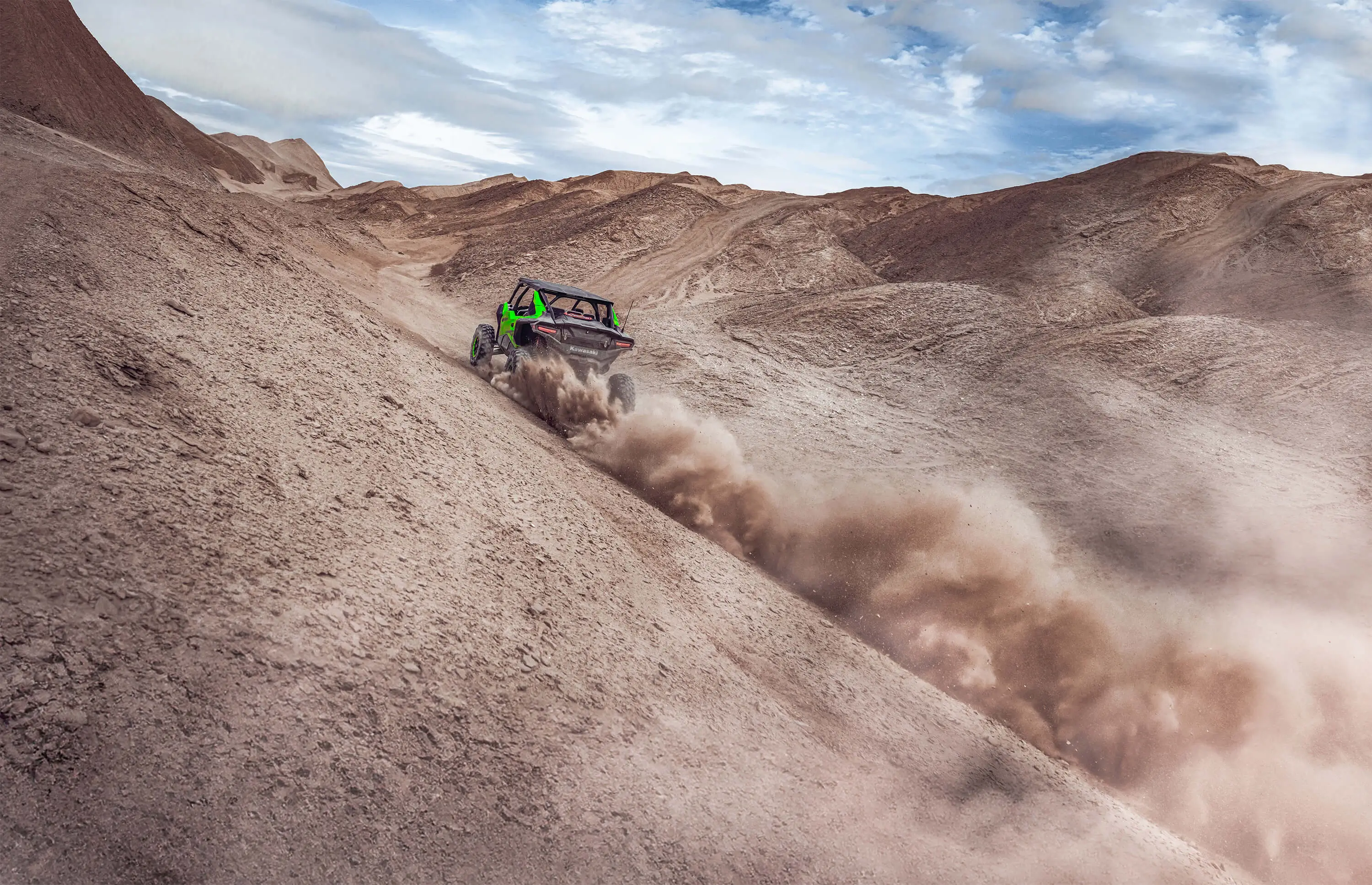 Front angle of a person driving a side x side off-road up the side of a sand dune.