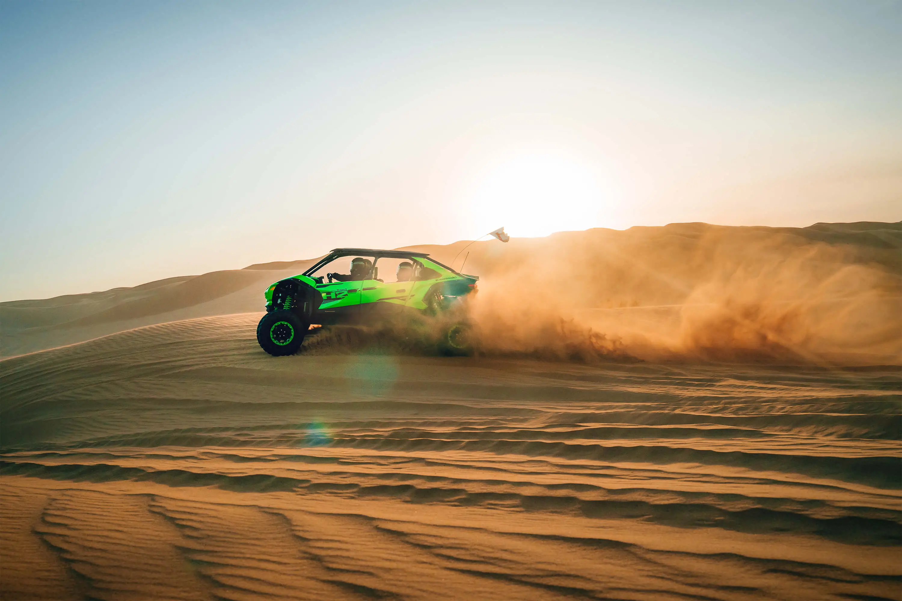 Side angle of a person driving a side x side off-road at sunset.
