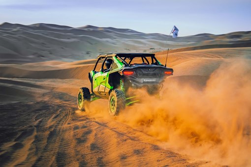 Rear angle of a person driving a side x side off-road. opens in a new window