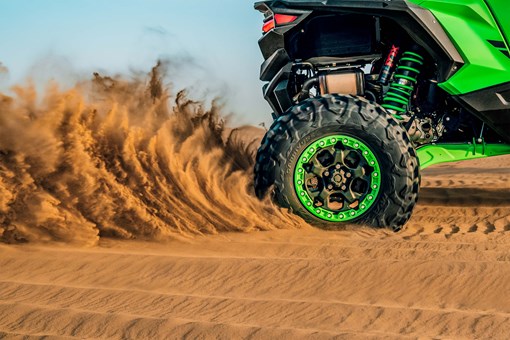 Close-up of a side x side wheel driving through sand off-road. opens in a new window