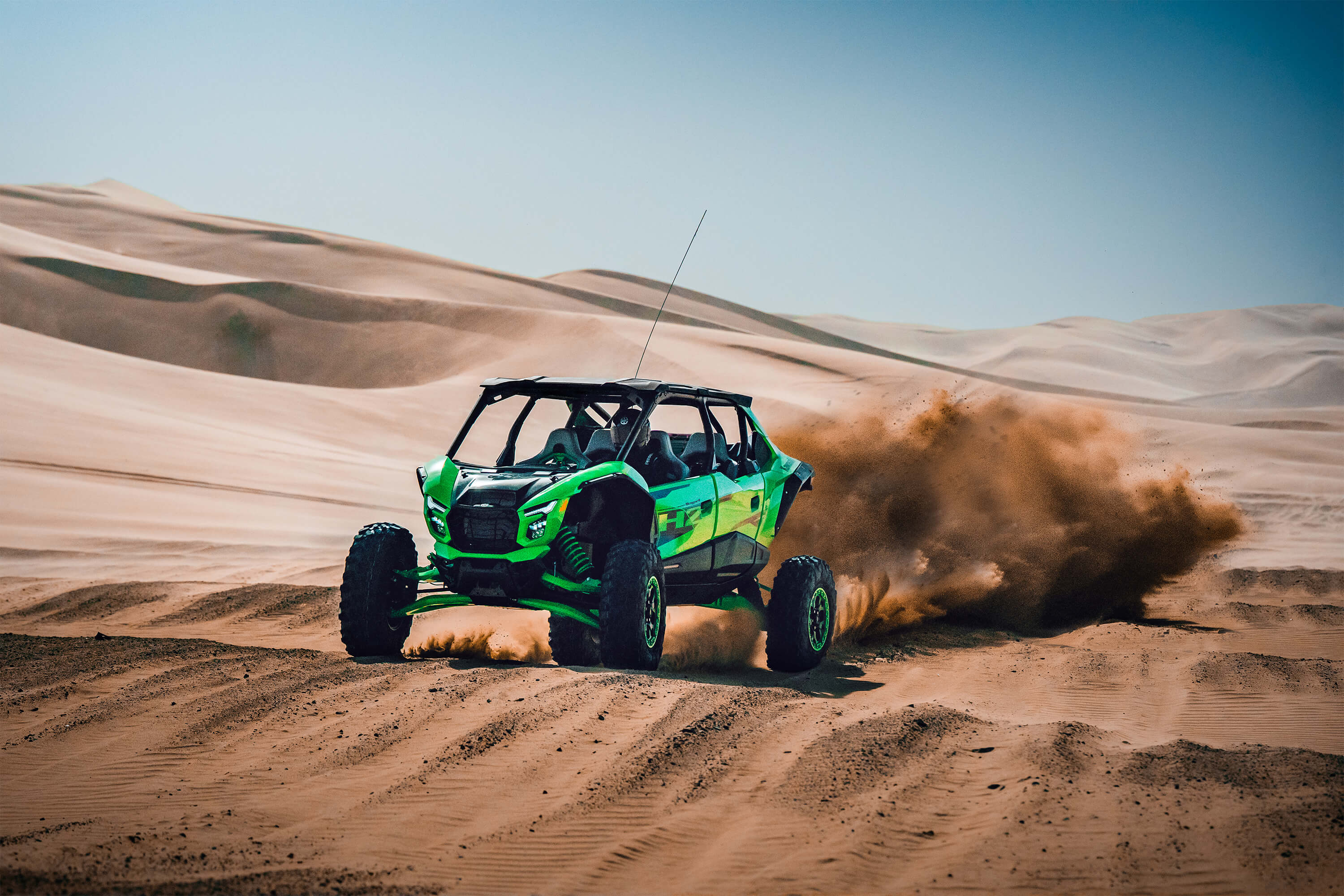 Front angle of a person driving a side x side off-road over large whoops.