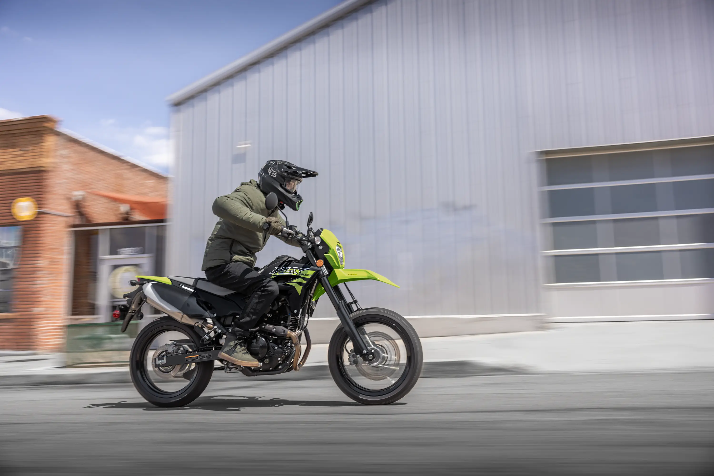 Side angle of a person riding a motorcycle on the street.