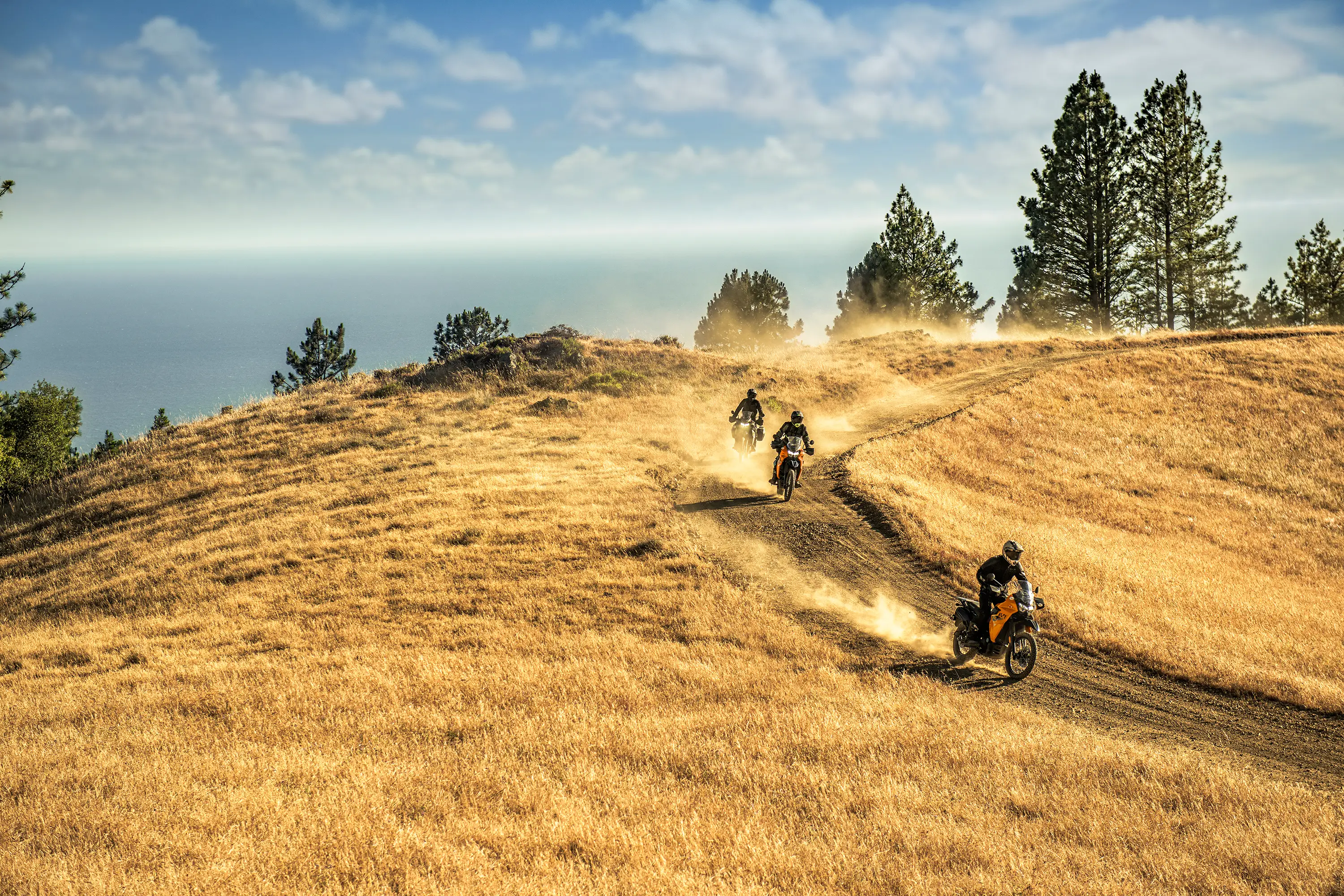 Three-quarter front angle of 3 people riding motorcycles off-road.