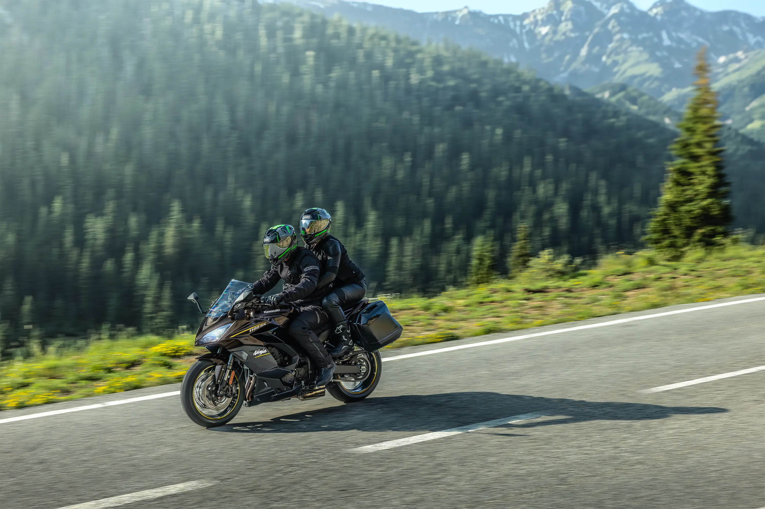 Side angle of two people riding a motorcycle on a highway.