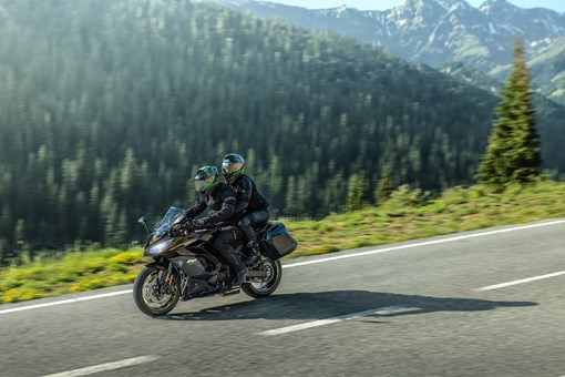 Side angle of two people riding a motorcycle on a highway. opens in a new window