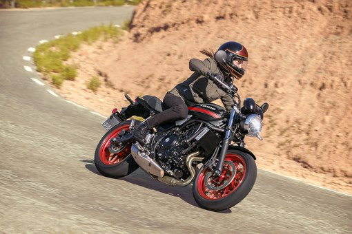 Three-quarter front angle of a person riding a motorcycle on a highway. opens in a new window