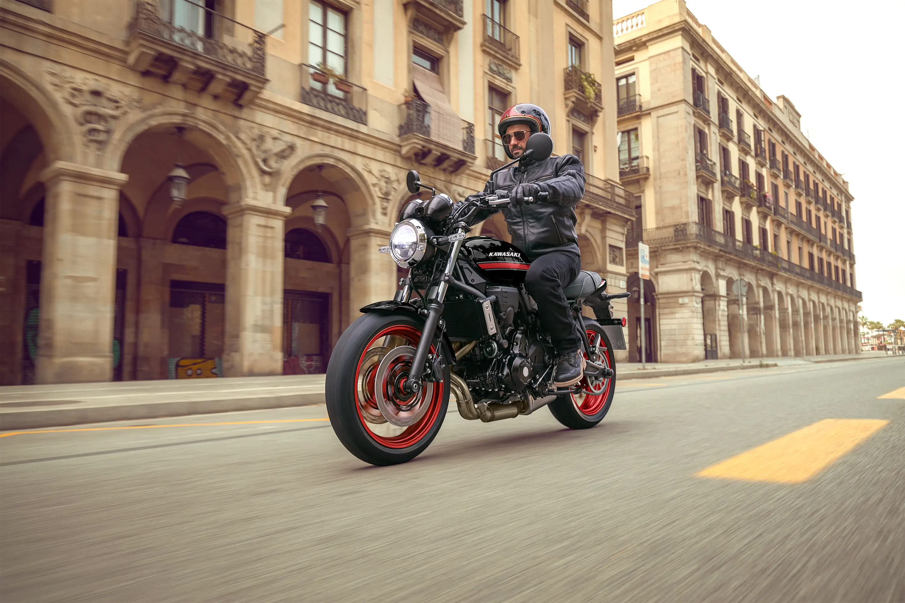 Three-quarter front angle of a person riding a motorcycle on the street.