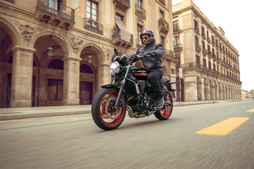 Three-quarter front angle of a person riding a motorcycle on the street. opens in a new window