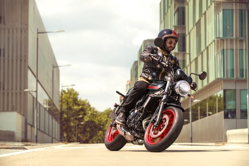 Three-quarter front angle of a person riding a motorcycle on the street. opens in a new window