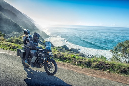 Side angle of a person riding a motorcycle next to an ocean view. opens in a new window