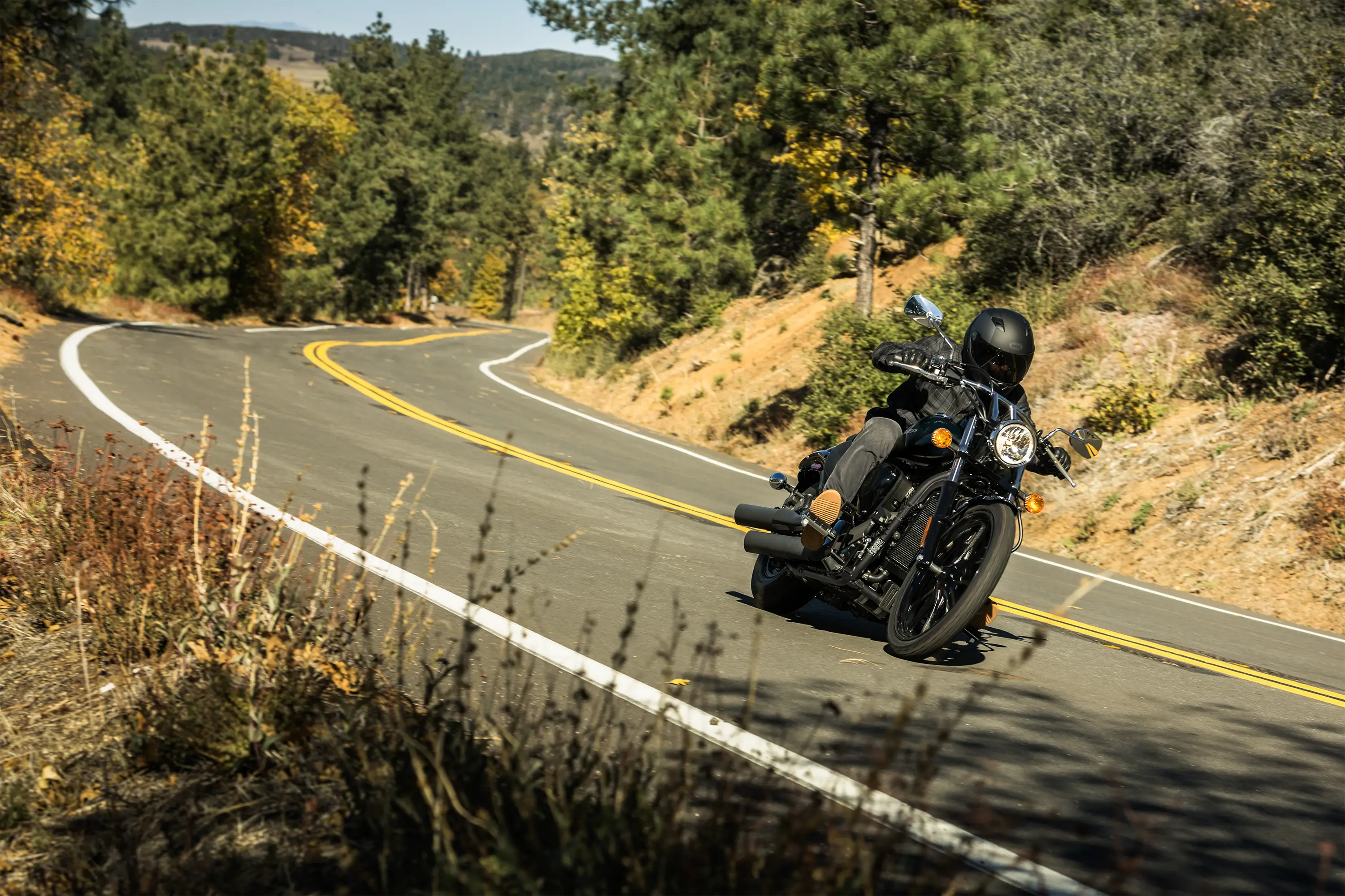 Three-quarter front angle of a person riding a motorcycle on a highway.