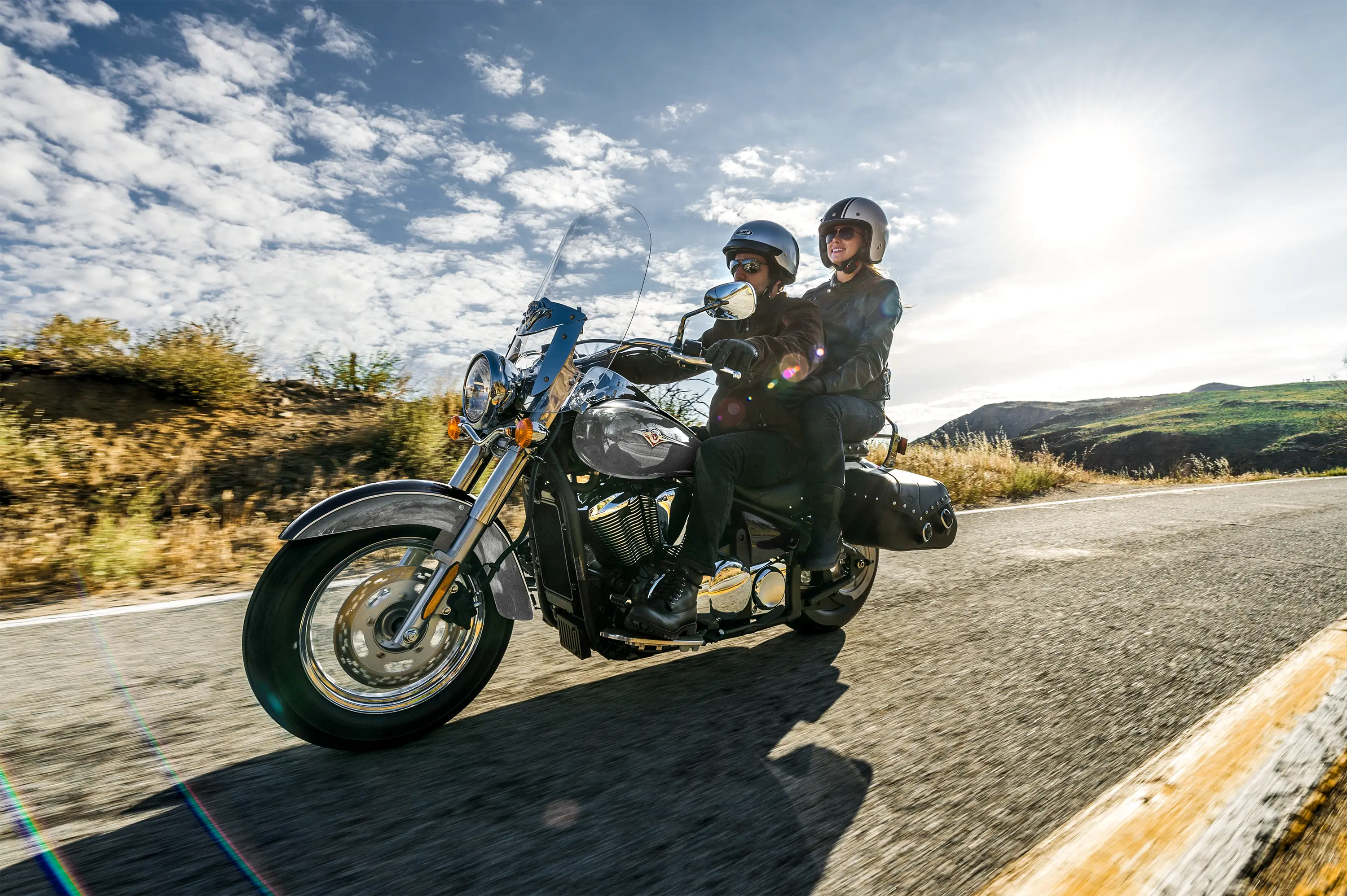 Three-quarter front angle of two people riding a motorcycle on a highway.