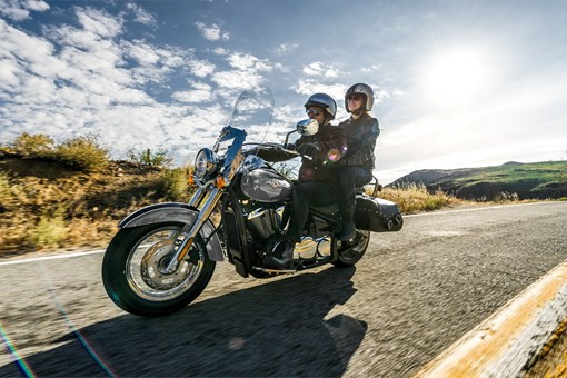 Three-quarter front angle of two people riding a motorcycle on a highway. opens in a new window