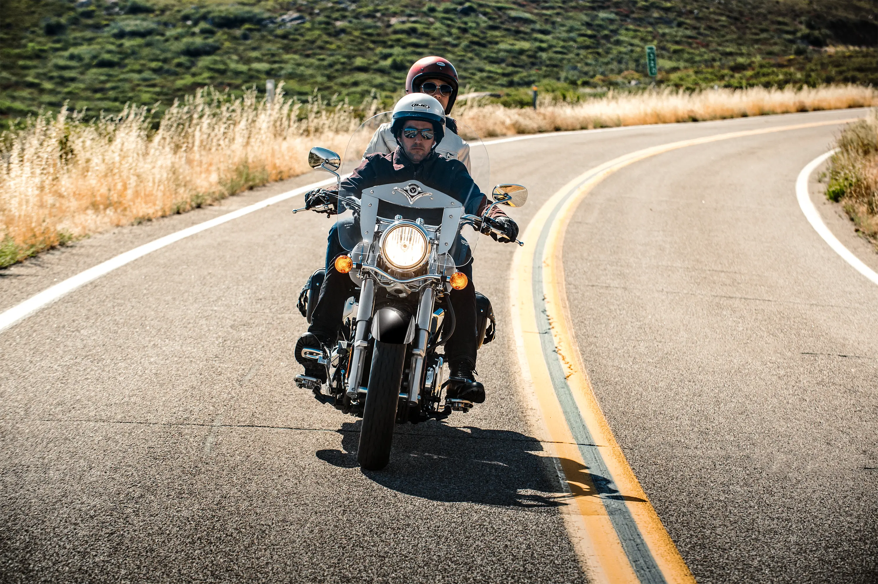 Front angle of two people riding a motorcycle on a highway.