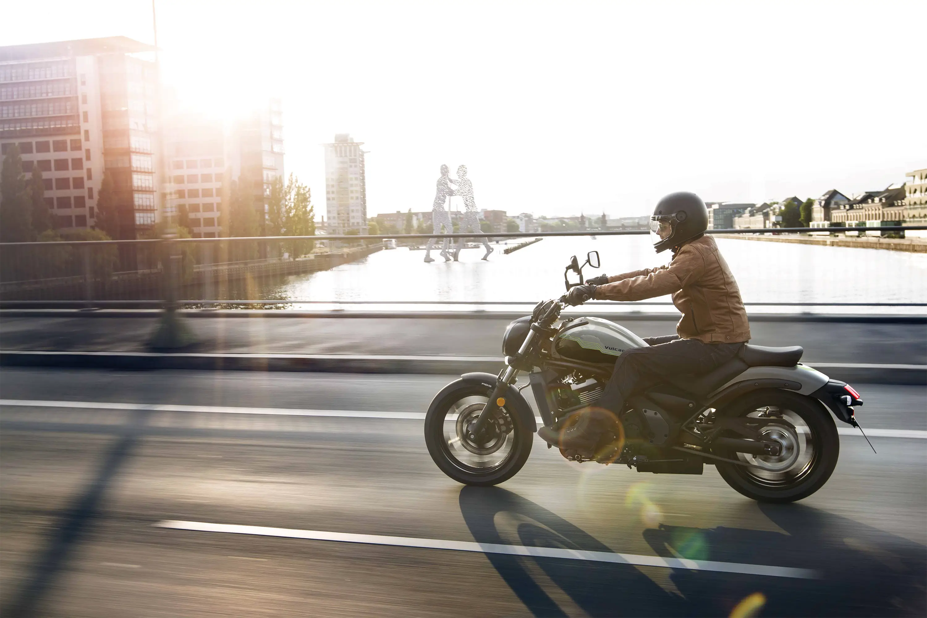Side angle of a person riding a motorcycle on the street.