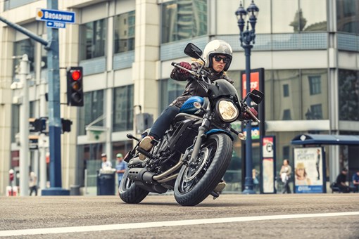 Front three-quarter angle of a person riding a motorcycle on the street. opens in a new window