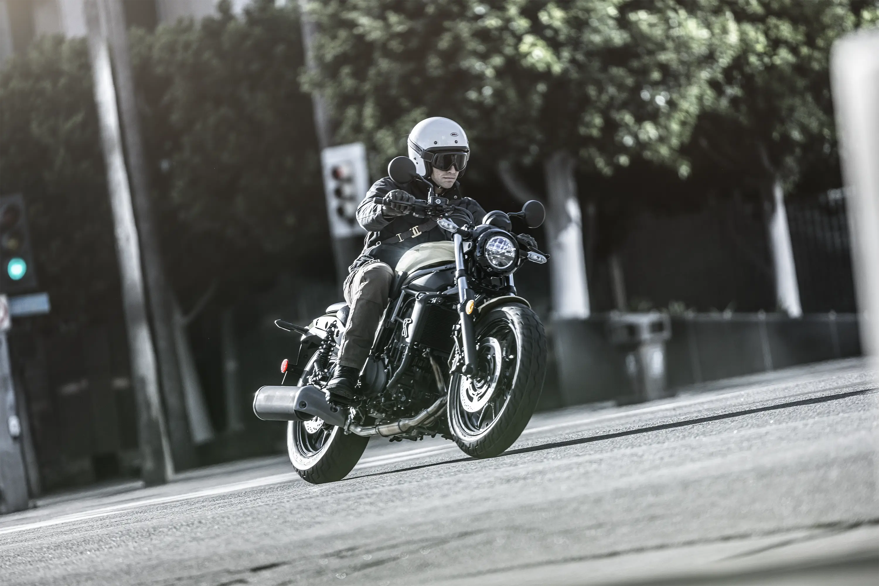Three-quarter front angle of a person riding a motorcycle on the street.