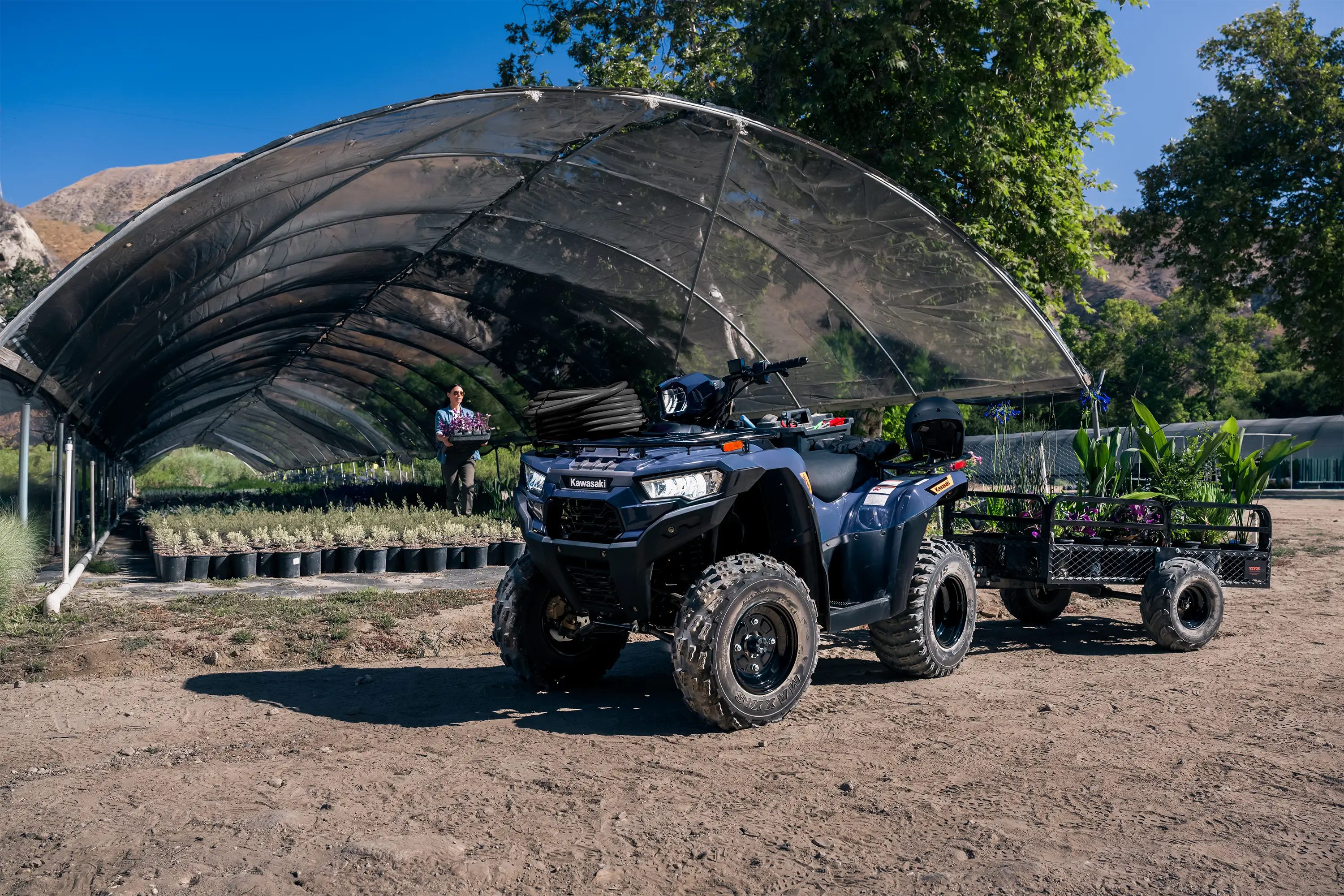 Three-quarter front angle of an ATV parked off-road with a trailer.
