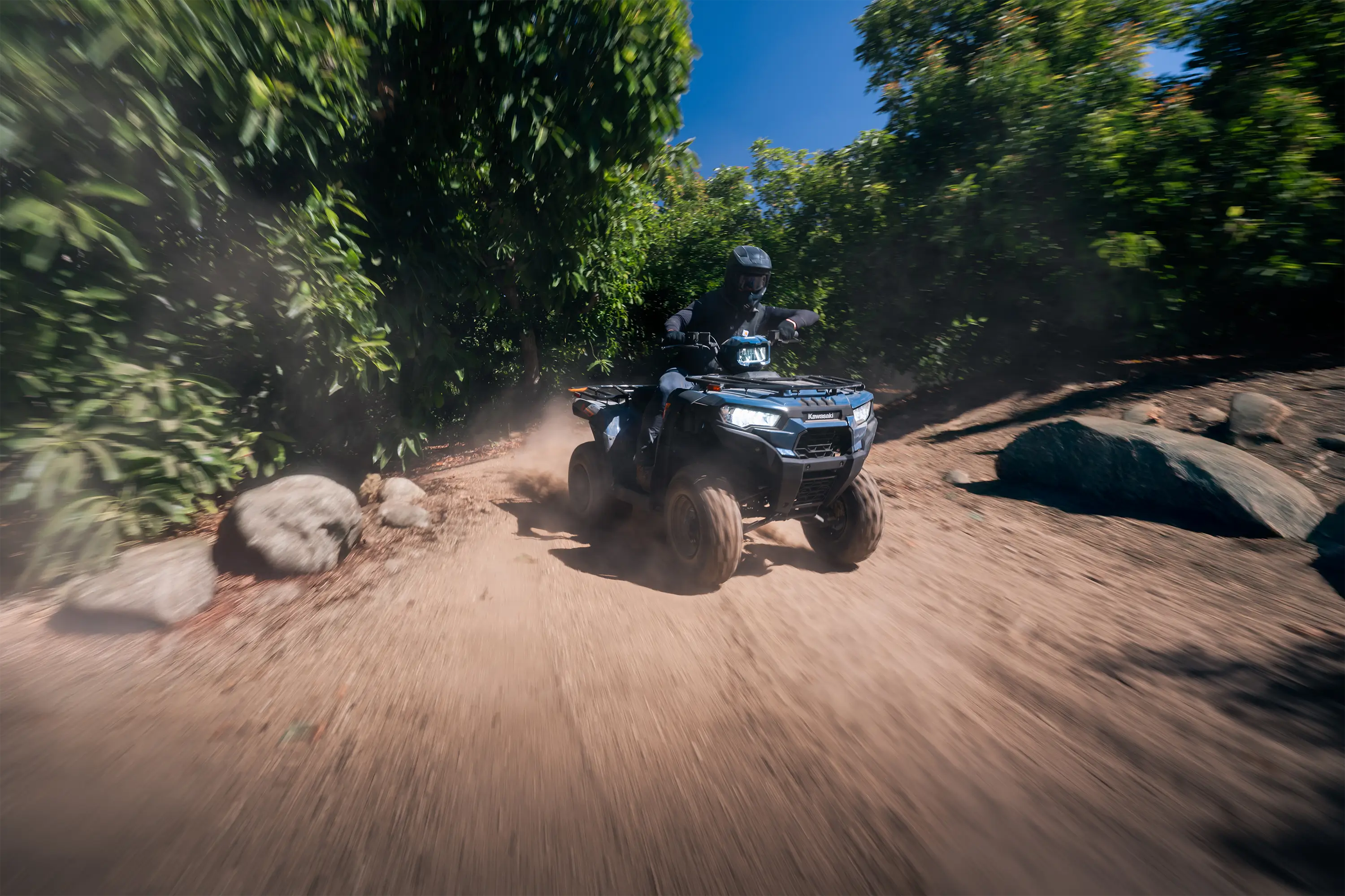Front three-quarter angle of a person riding an ATV on a trail.