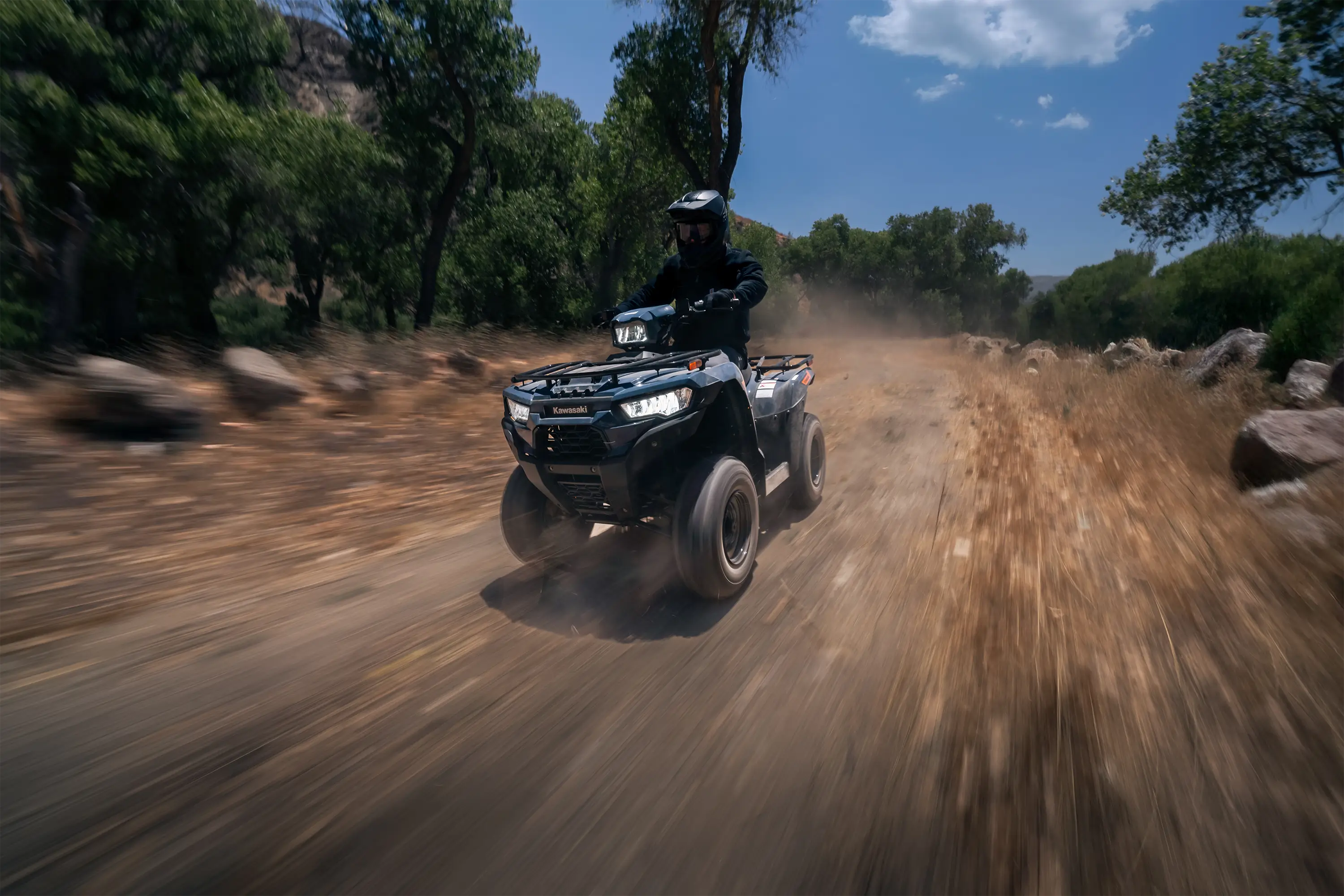 Three-quarter front angle of a person riding an ATV on a trail.