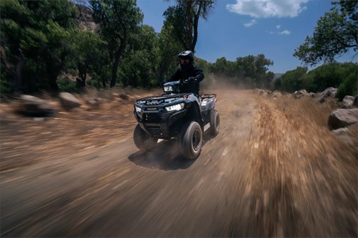 Three-quarter front angle of a person riding an ATV on a trail. opens in a new window