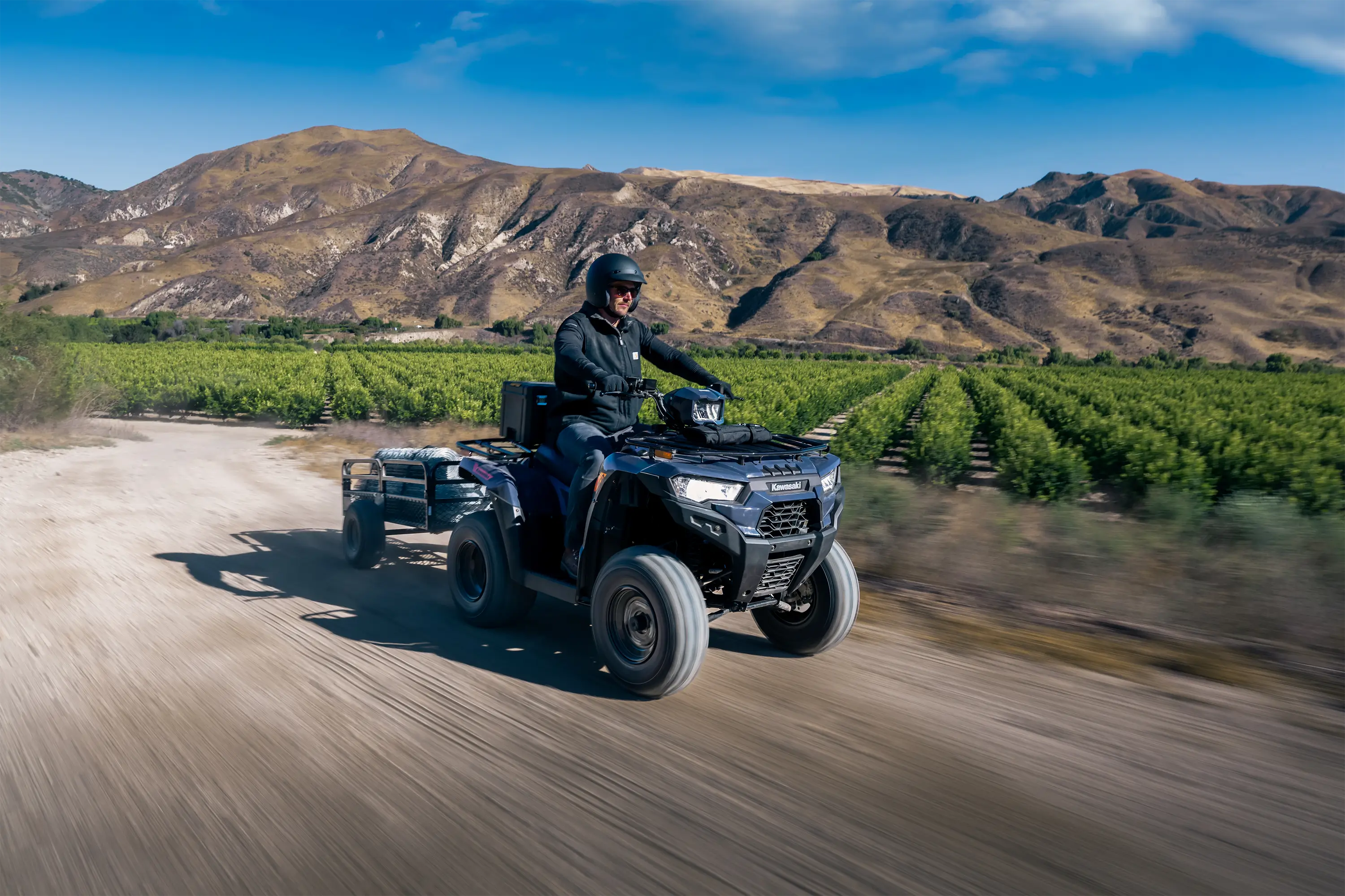 Three-quarter front angle of a person riding an ATV off-road.