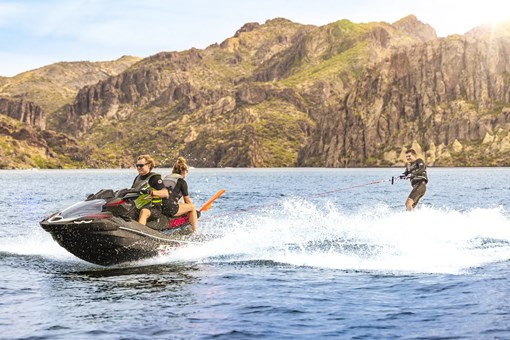 Profile angle of a person wake boarding behind a personal watercraft on the water. opens in a new window