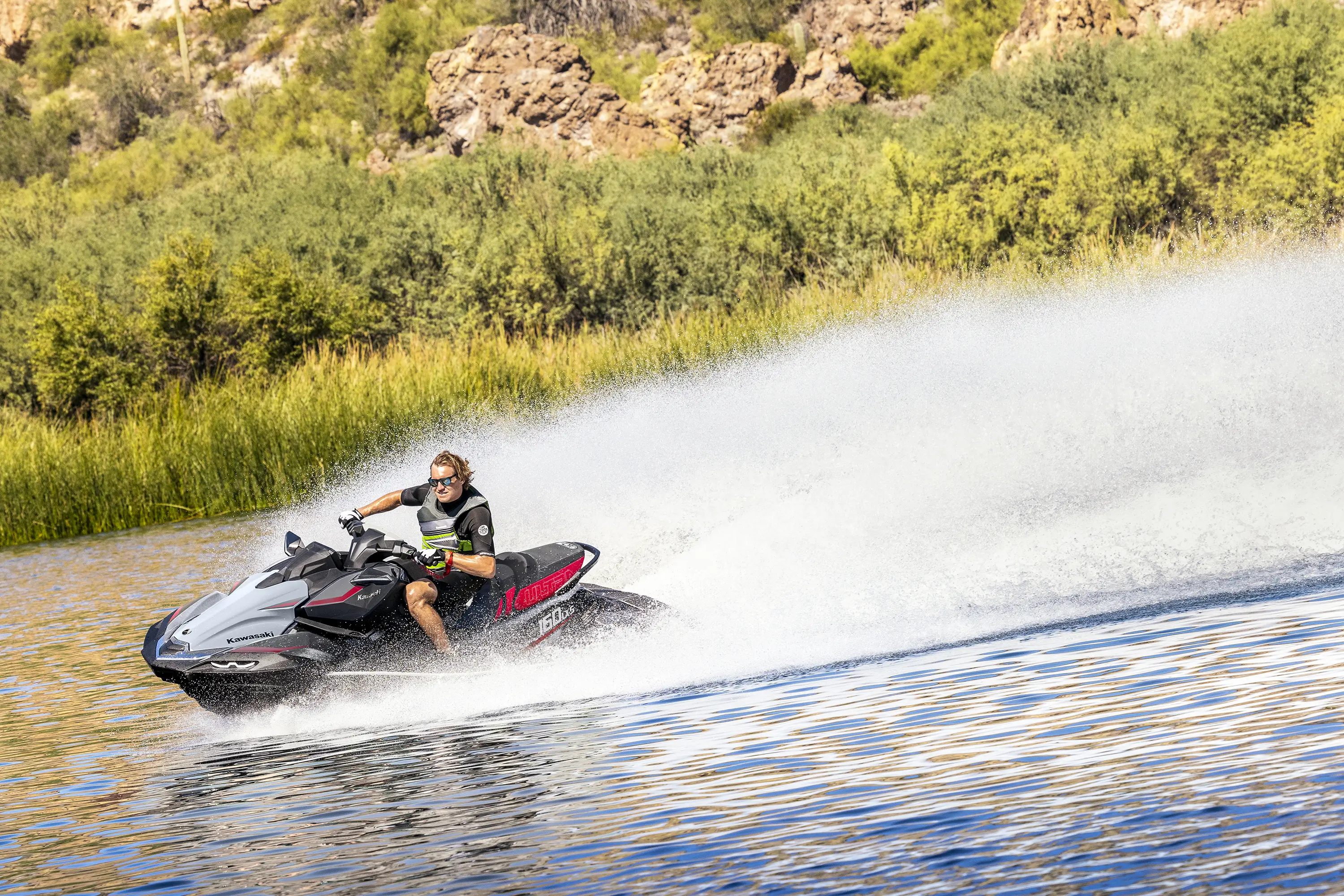 Side angle of a person on a personal watercraft on the water.