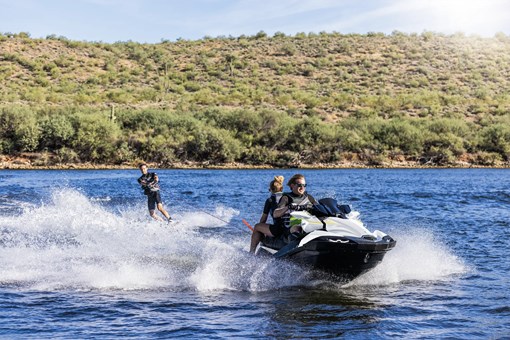 Front angle of a person wake boarding behind a personal watercraft on the water. opens in a new window