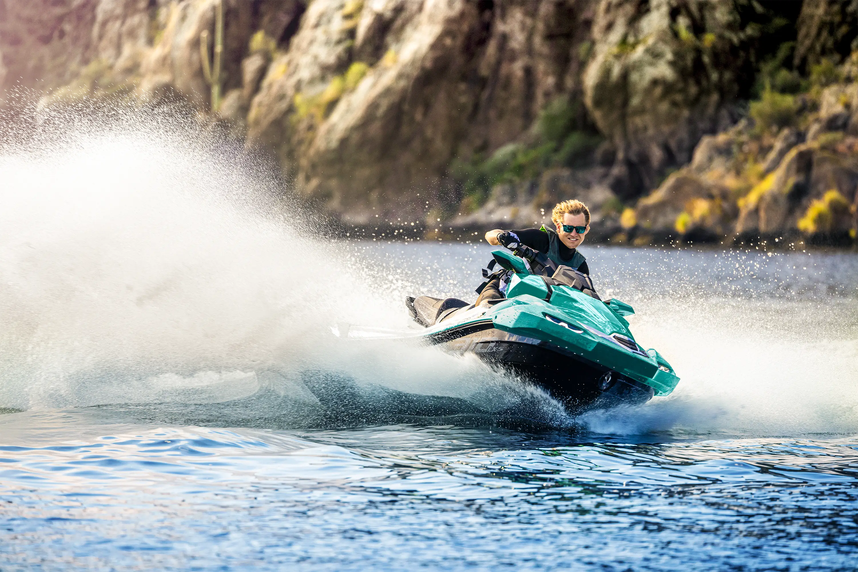 Front three-quarter angle of a person on a personal watercraft on the water.