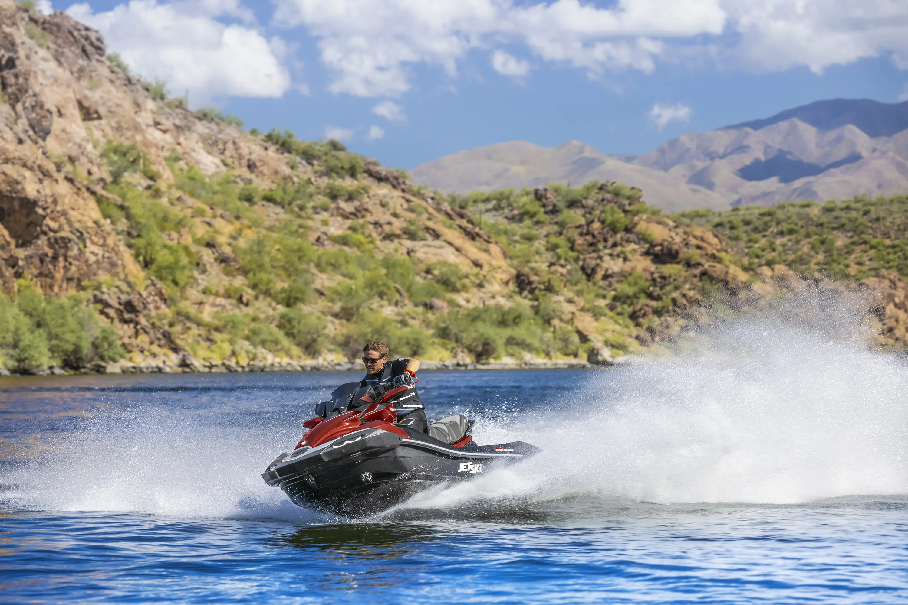Front three-quarter angle of a person on a personal watercraft on the water.