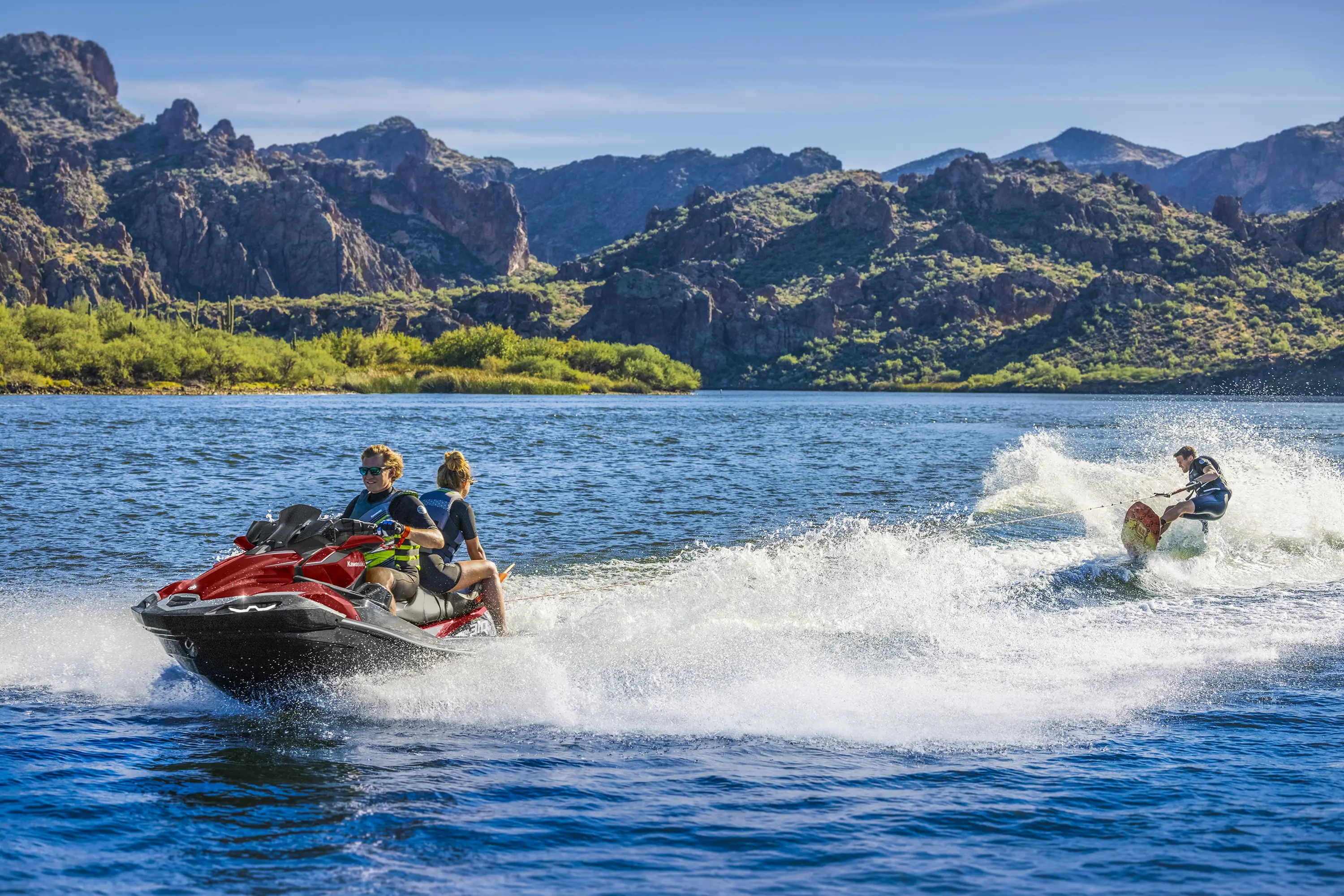 Front three-quarter angle of a person waking boarding behind a personal watercraft on the water.