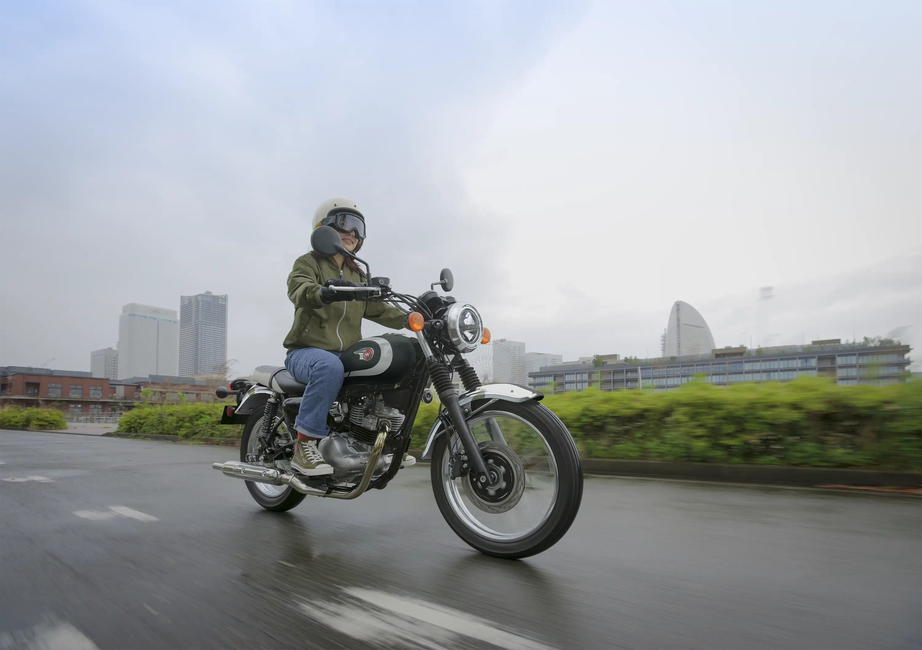 Three-quarter front angle of a person riding a motorcycle on the street.