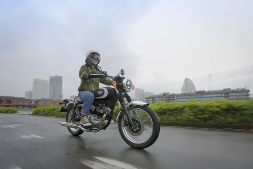 Three-quarter front angle of a person riding a motorcycle on the street. opens in a new window