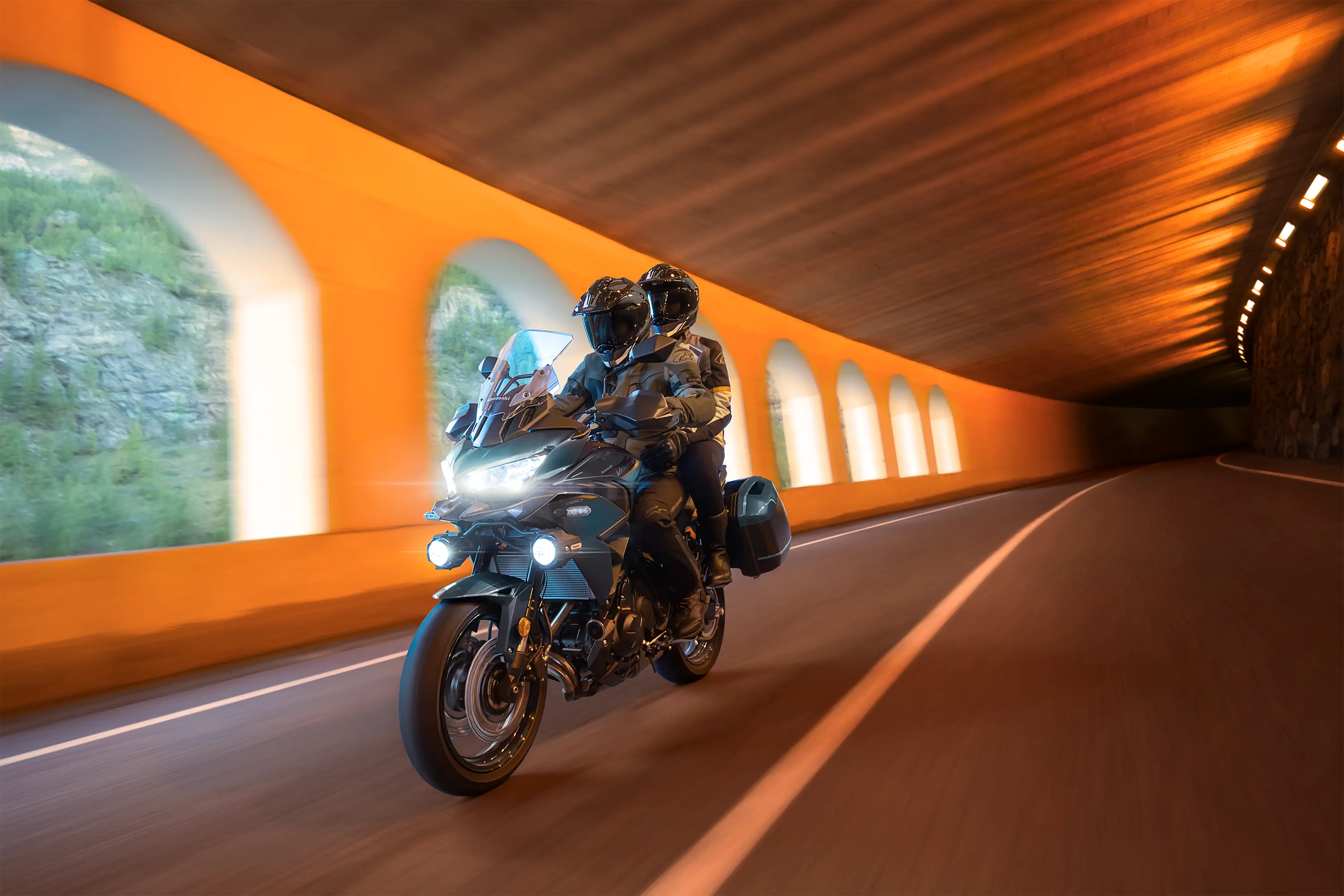 Three-quarter front angle of a person riding a motorcycle in a tunnel.
