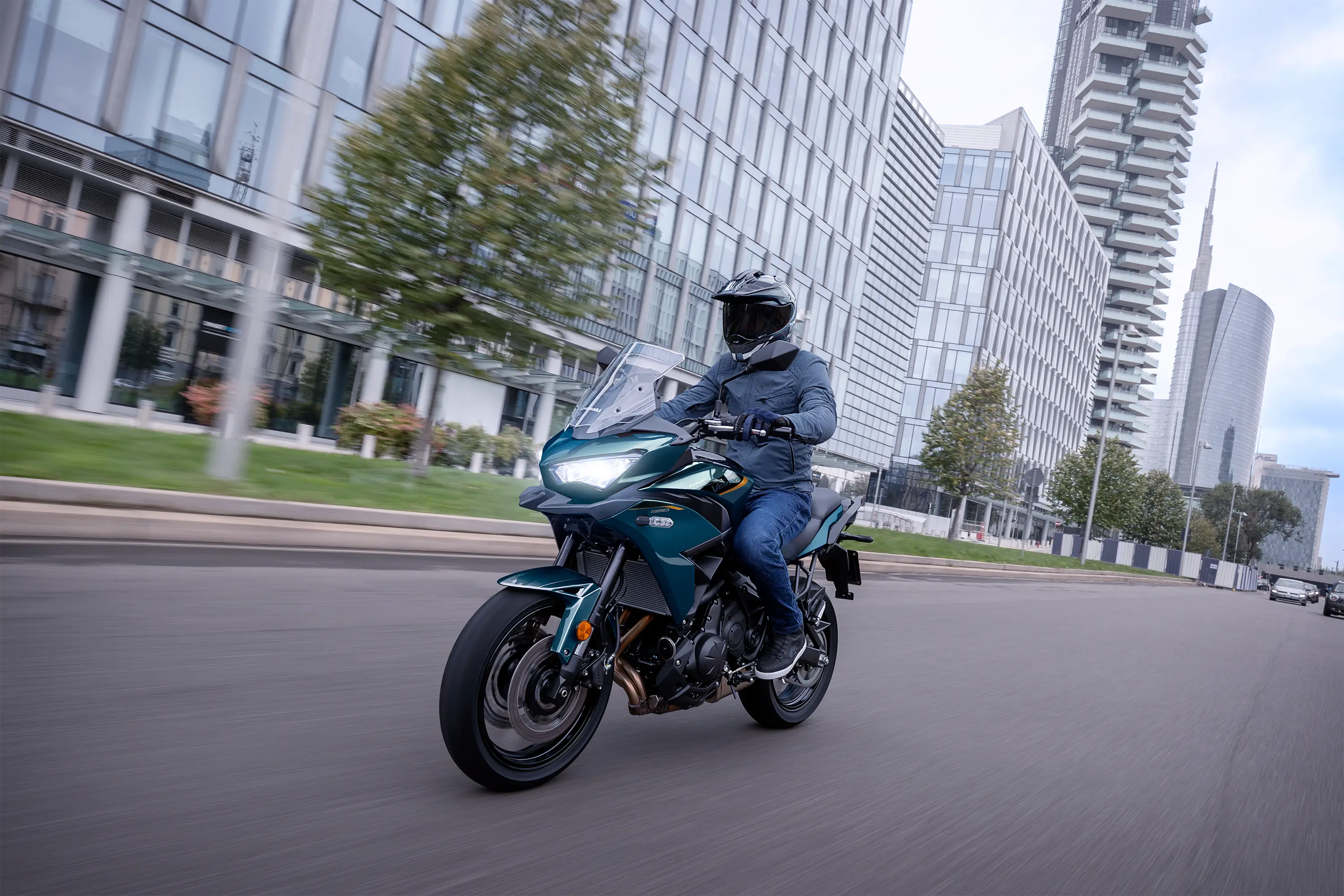 Three-quarter front angle of a person riding a motorcycle on the street.