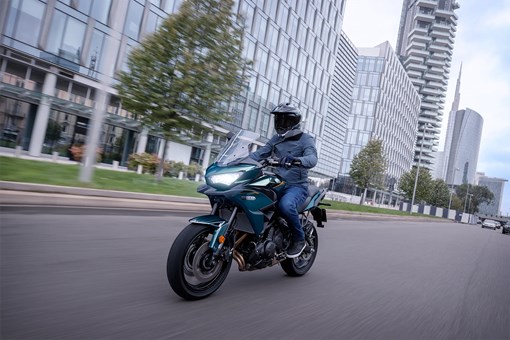 Three-quarter front angle of a person riding a motorcycle on the street. opens in a new window