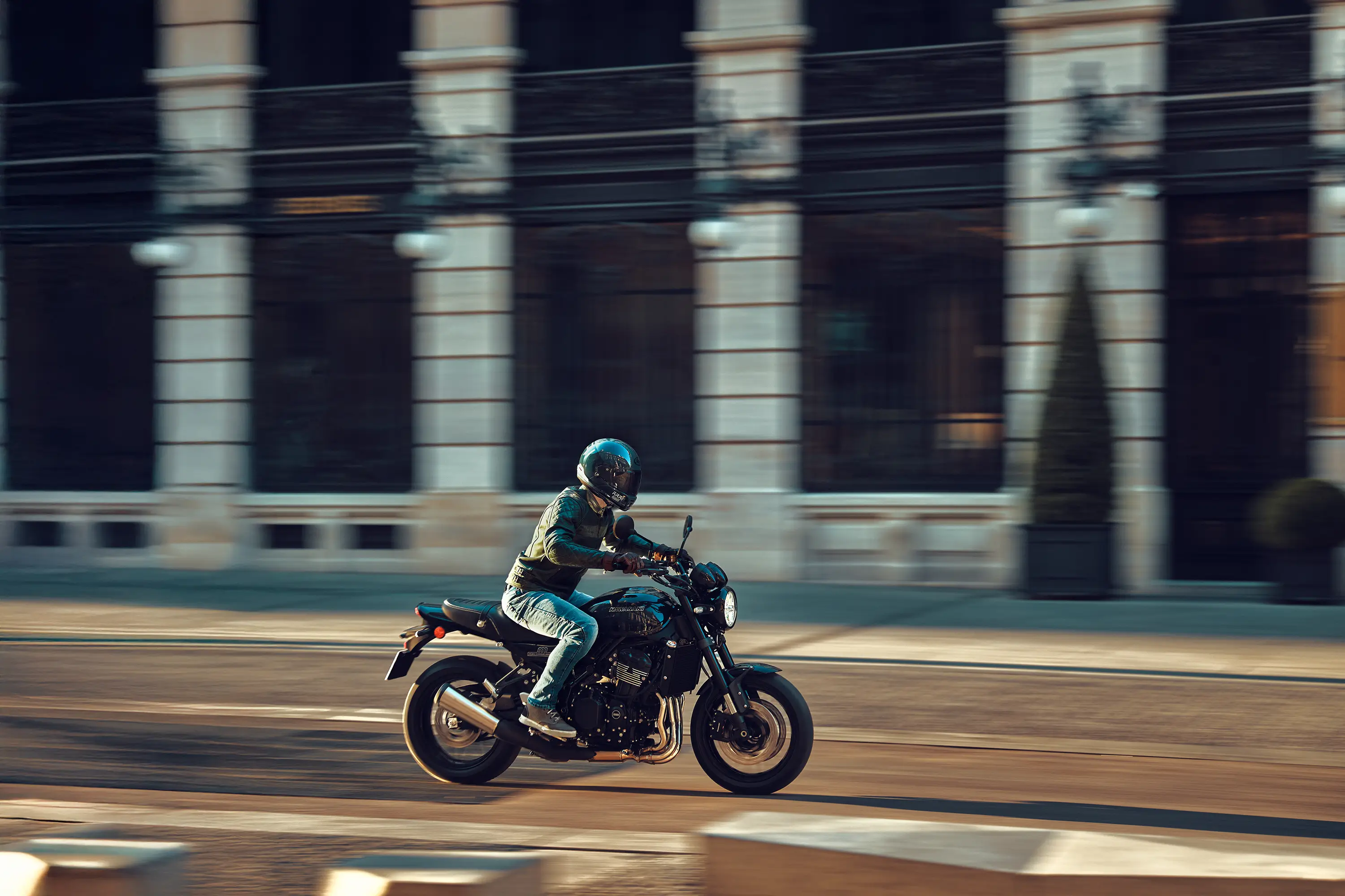 Side angle of a person riding a motorcycle on a town road.
