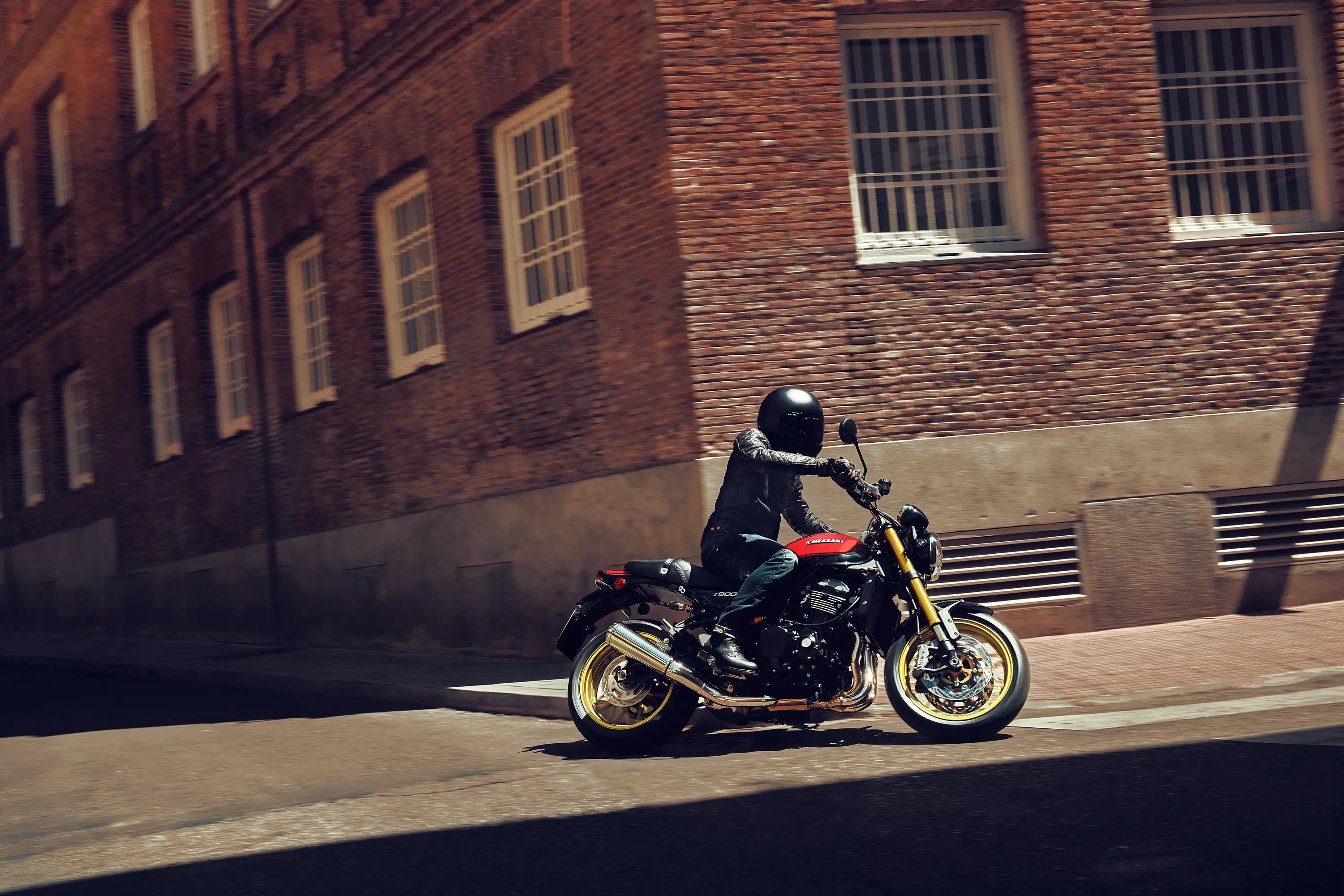 Profile view of a person riding a motorcycle on a city street.