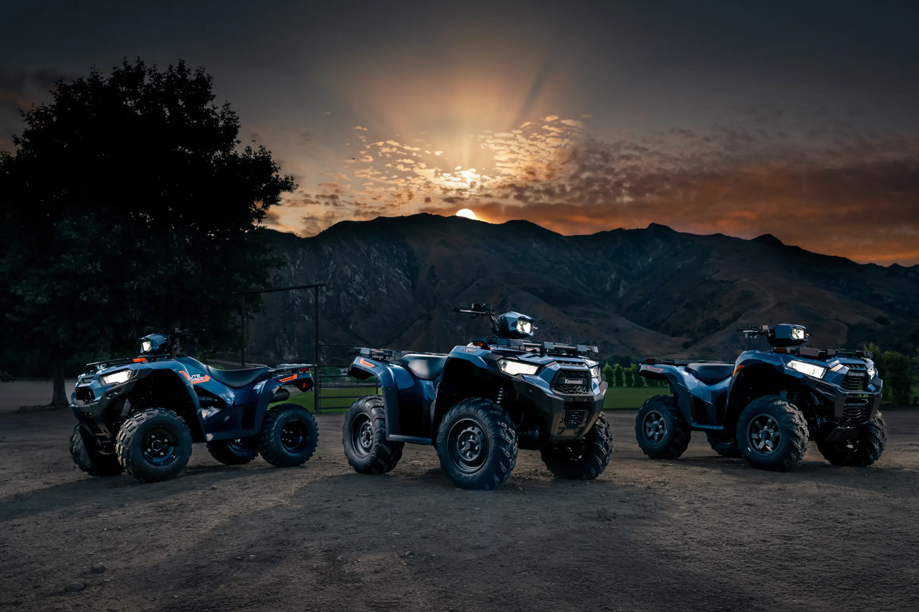 Three ATVs staged in front of a mountain.