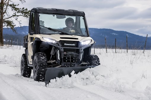 Front angle of a person plowing snow with their side x side. opens in a new window