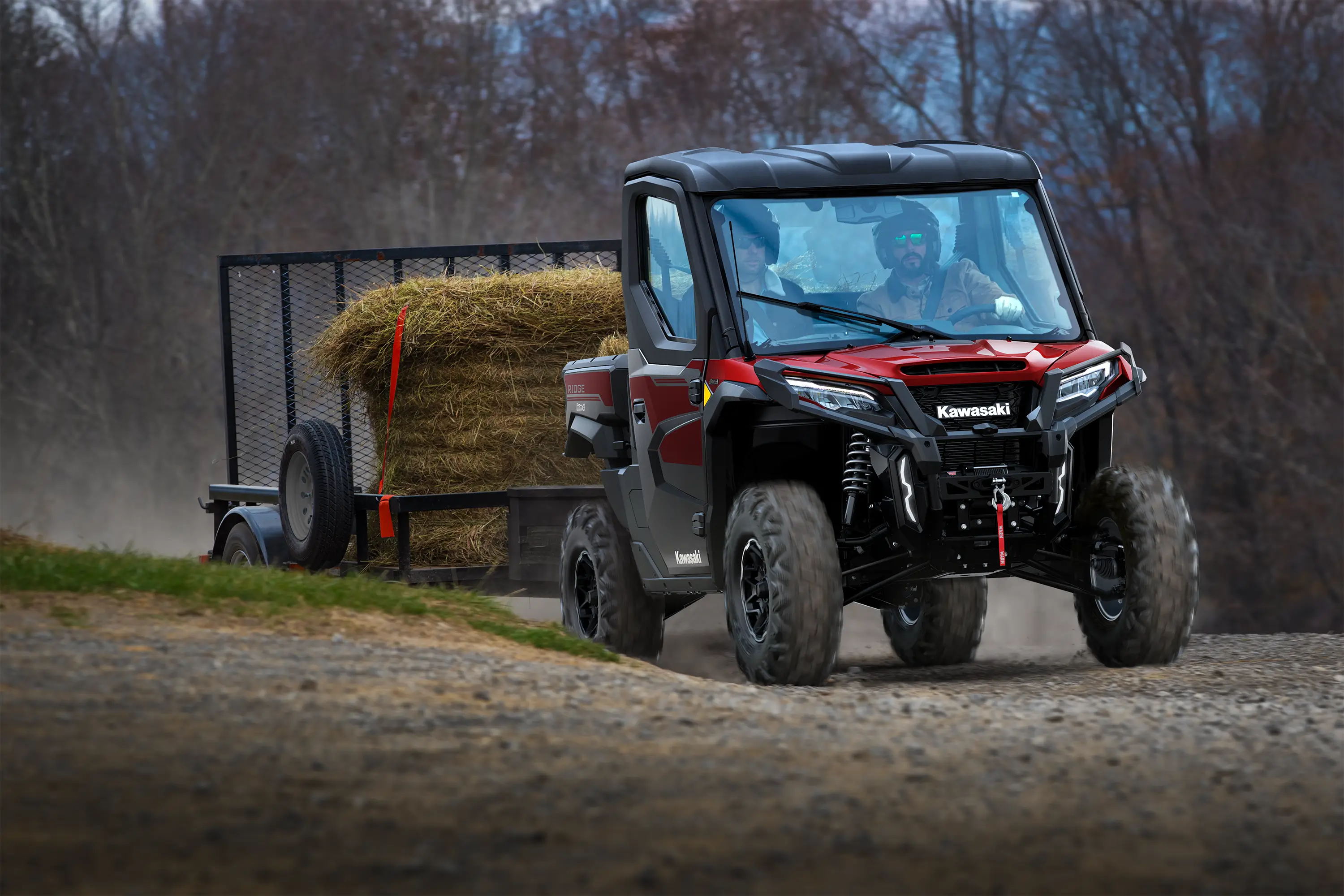 Front angle of a side x side towing a trailer on a gravel road.