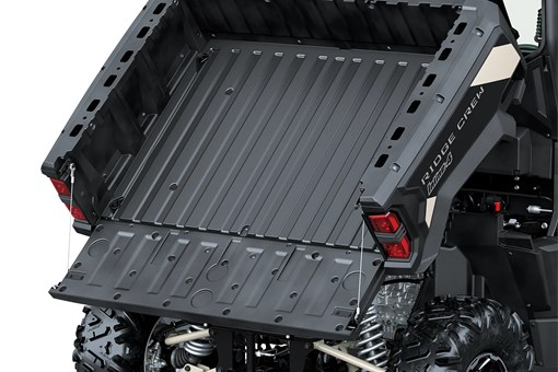 A full view of the tilting cargo bed of a side x side staged in a white studio background. opens in a new window