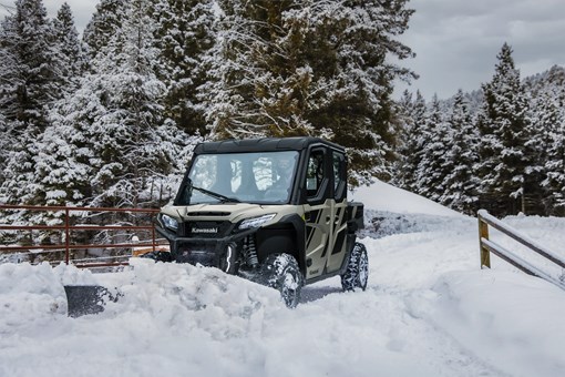 Front angle of a person plowing snow with their side x side. opens in a new window