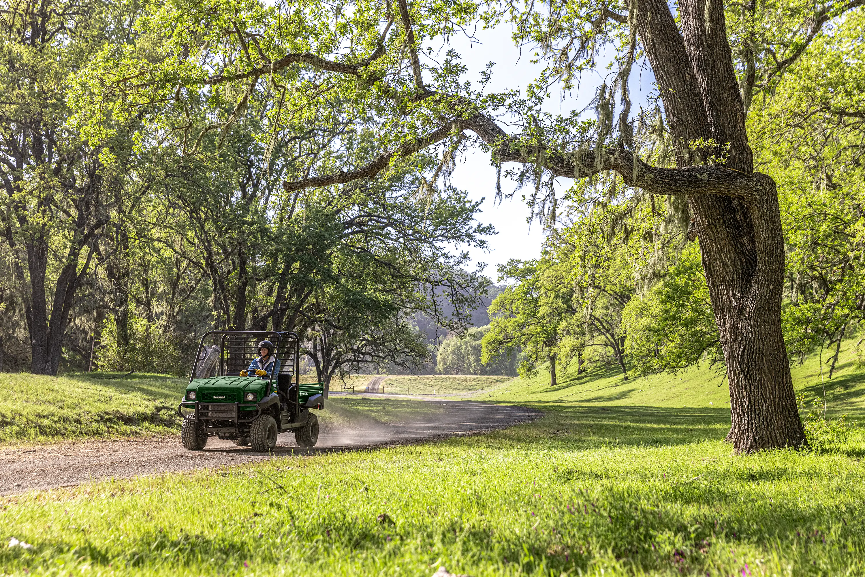 Three-quarter front angle of a person driving a side x side at a ranch.