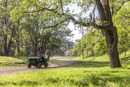 Three-quarter front angle of a person driving a side x side at a ranch. opens in a new window