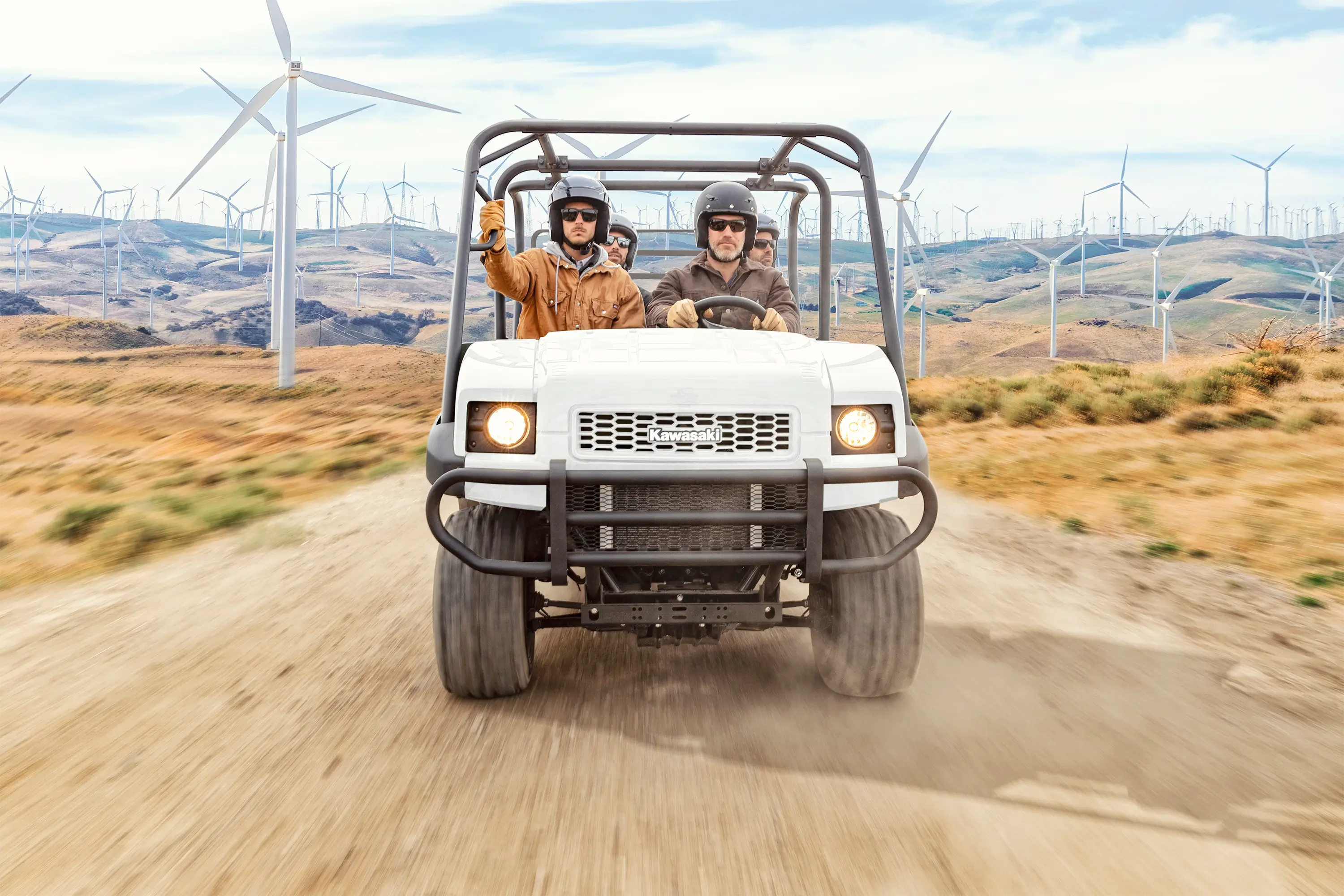 Front angle of four people riding a side x side on a jobsite.