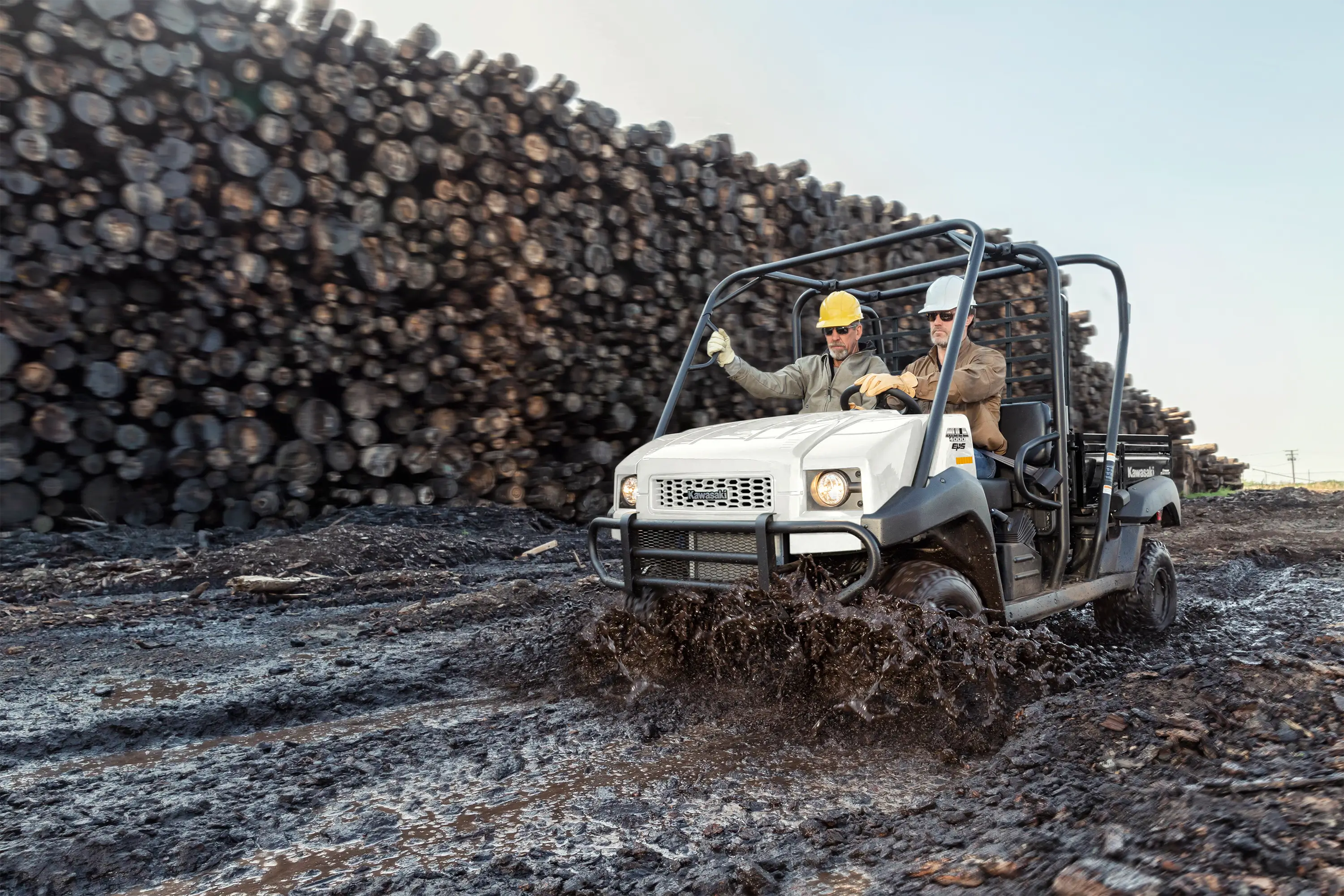 Three-quarter front angle of two people riding a side x side on a jobsite.