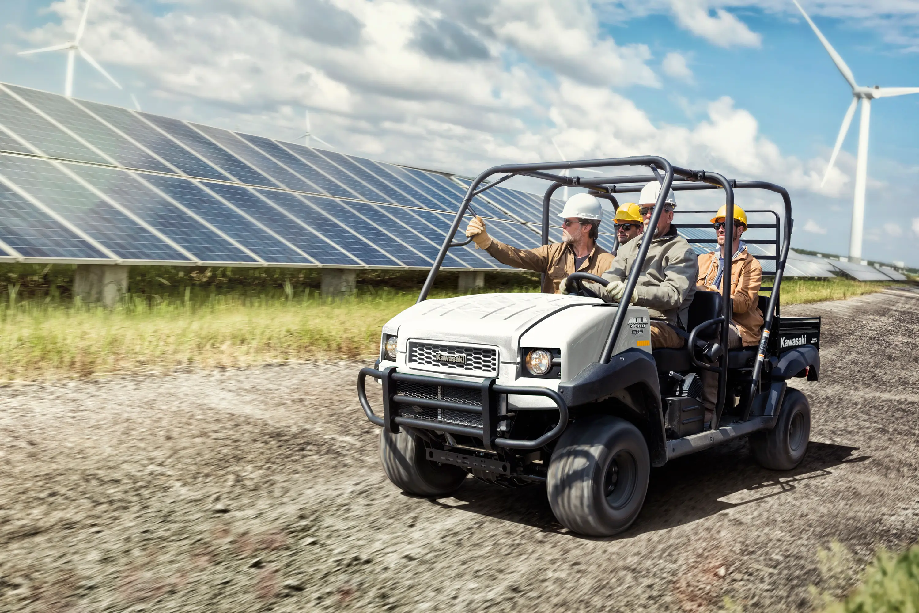 Three-quarter front angle of four people riding a side x side on a jobsite.