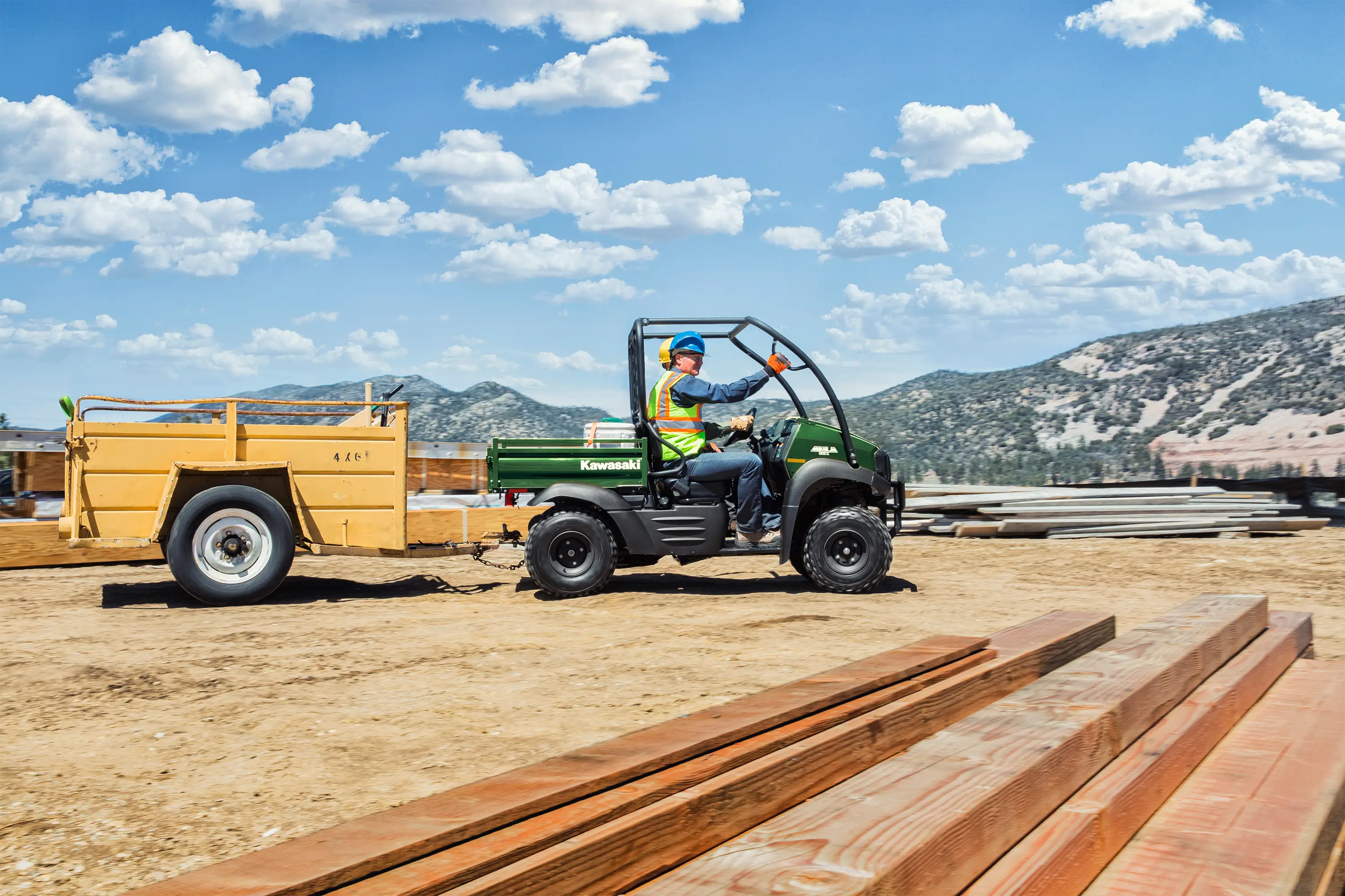 Side view of a person driving a side x side through an industrial worksite.